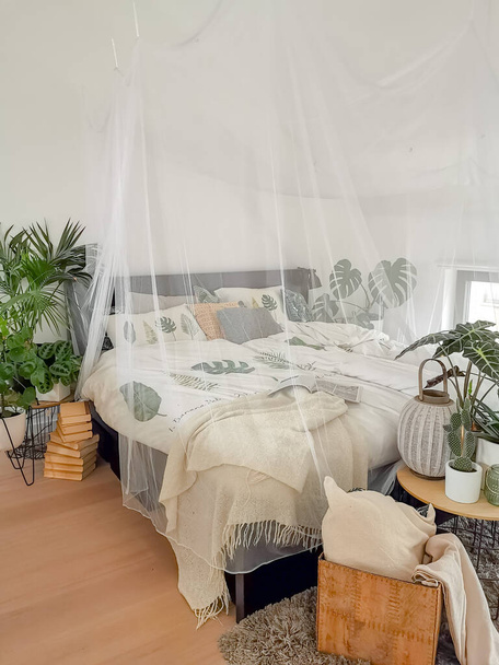 Яскрава біла спальня наповнена численними кімнатними рослинами і затоплена природним світлом
 - Фото, зображення