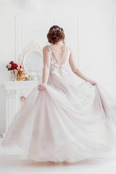 the bride in a gently pink wedding dress is dancing in the studio showing off a beautiful back. The skirt is beautifully developing. there is a place to insert text - Foto, imagen