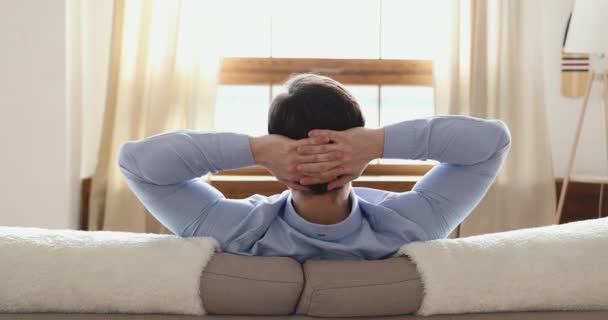 Mindful young guy leaning on comfortable sofa alone at home. - Кадри, відео