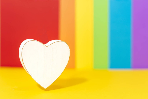 Bílé dřevěné srdce na pozadí s barvami LGBT hnutí. Barvy příznaku pohybu LGBT - Fotografie, Obrázek