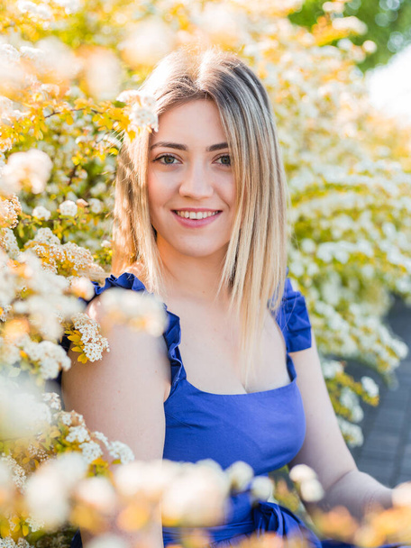 Sensual calm portrait of beautiful hipster woman in blooming bush with white flowers of spirea. - Zdjęcie, obraz