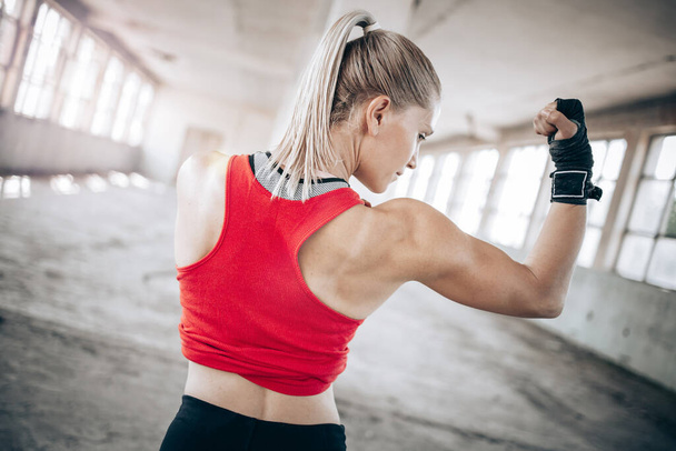Fit blonde girl showing her arm muscles. Strong women, active lifestyle - Фото, изображение
