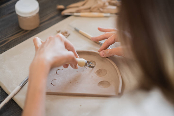 Nahaufnahme eines Töpfermeisters, Ton schneiden Spezialwerkzeug. Künstlerin schneidet mit einem Holzschlaufenwerkzeug - Foto, Bild