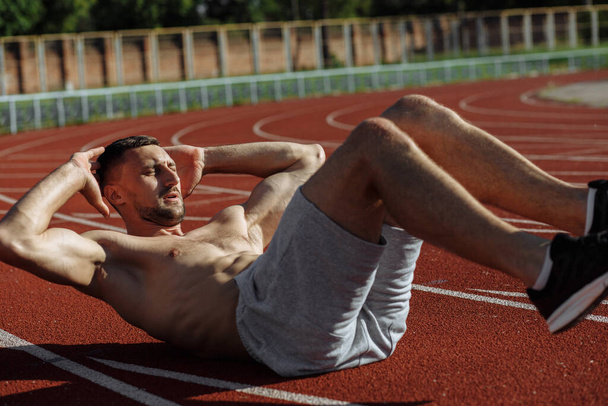 Shirtloser muskulöser Mann beim Bauchmuskeltraining draußen. Sportler. Starker Mann - Foto, Bild