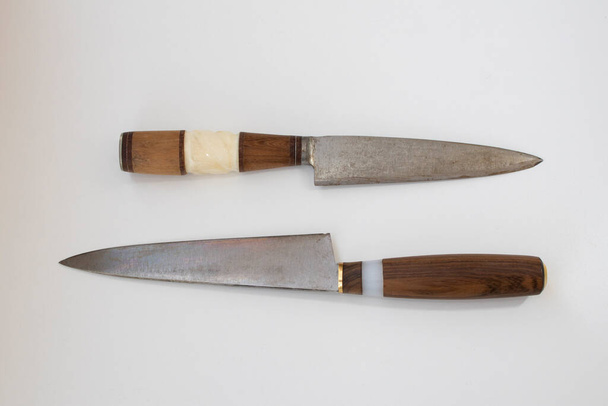 Két régi vintage házi konyha vagy háztartási kés egy fa nyéllel, elefántcsont részleteket és egy penge egy fűrészlap elszigetelt fehér háttér - Fotó, kép