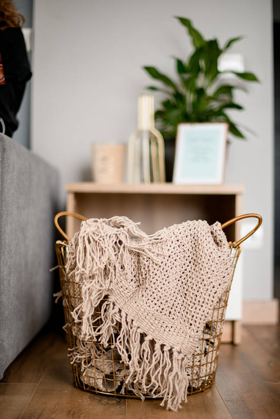 wicker basket with plaid inside standing on the floor in the room. - Φωτογραφία, εικόνα