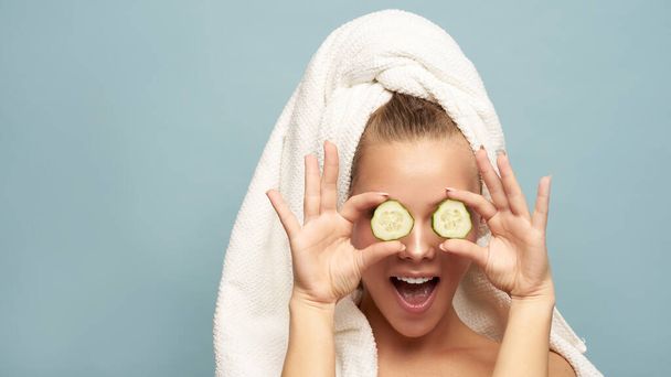 Beautiful young woman holding slices of cucumber. Skin care and treatment, spa, natural beauty and cosmetology - Foto, Imagem