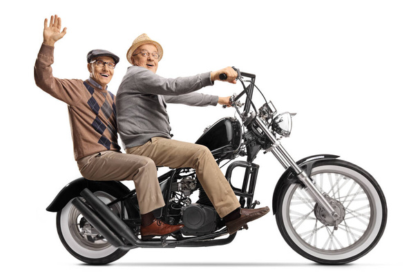 Two elderly men on a chopper motorbike waving and looking at the camera isolated on white background - Foto, Imagem