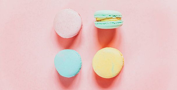 Sweet almond colorful pink blue yellow green macaron or macaroon dessert cake isolated on trendy pink pastel background. French sweet cookie. Minimal food bakery concept. Flat lay top view copy space - 写真・画像