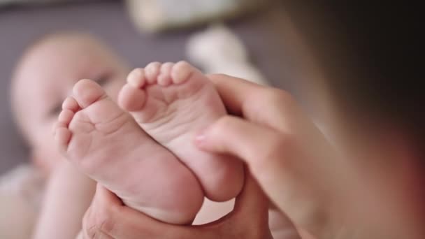 Madre massaggiando e solleticando i piccoli piedi del bambino. primo piano rallentatore colpo
 - Filmati, video