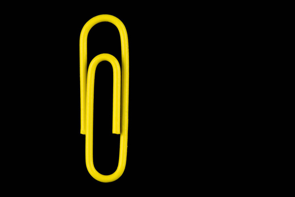 Одинарна жовта скріпка паперу ізольована на чорному тлі
 - Фото, зображення