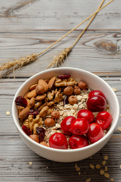 tazón de granola de avena con fresas y frutos secos sobre tabla de madera blanca para una salud saludable
 - Foto, imagen