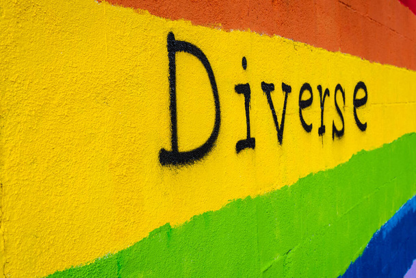 Poziomy obraz kolorystyczny z bocznym widokiem ściany z kolorami flagi LGBT i napisanym na niej słowem "zróżnicowany" - Zdjęcie, obraz