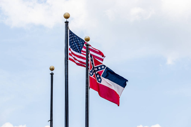 Pola flagowe z flagą Stanów Zjednoczonych Ameryki i flagą stanu Mississippi machające na wietrze przeciwko błękitnemu niebu. - Zdjęcie, obraz