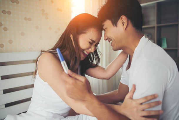 Щаслива пара посміхається після того, як дізнається позитивний тест на вагітність в спальні
  - Фото, зображення