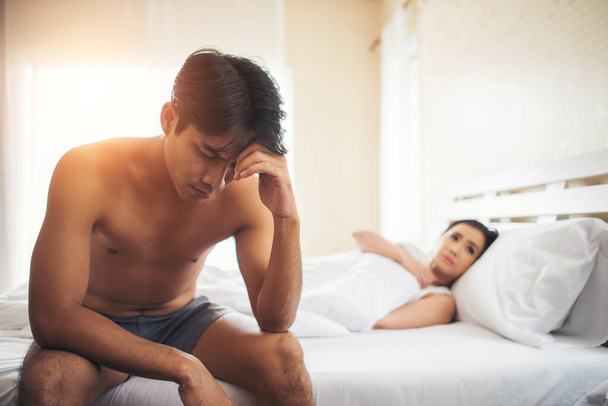 Deprimido homem sentado na cama no quarto tem problema com sua esposa
 - Foto, Imagem