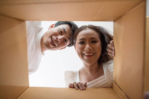 Casal feliz abrindo uma caixa e olhando para dentro do produto
 - Foto, Imagem