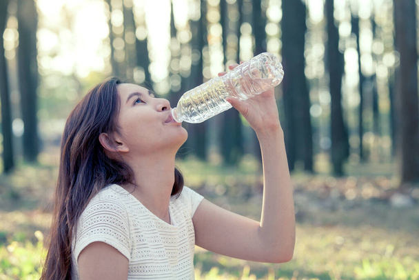 Jovem mulher asiática bebendo água no parque natural em tom de cor vintage
 - Foto, Imagem