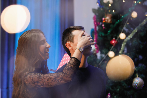 L'uomo e una donna si abbracciano e si congratulano vicino a un albero di Natale decorato. - Foto, immagini