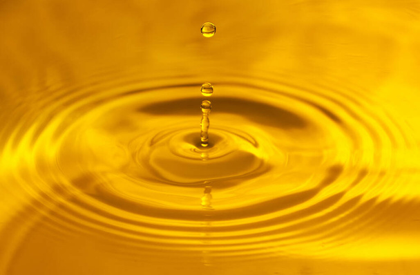 Fondo amarillo, textura. Gotas cayendo en el agua y círculos caminando sobre el agua, con reflejo. - Foto, imagen