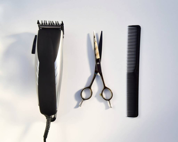 Hairdressing various accessories on a light background. the concept of the hairdressing beauty industry. hairdressing scissors and hair clipper with comb - Fotografie, Obrázek