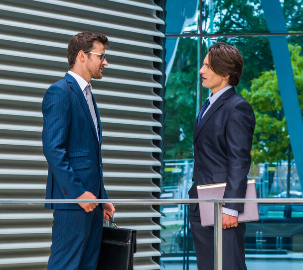 Teamwork and business concept. Confident businesspersons in formal wear having conversation about banking and financial markets in front of office building. - 写真・画像