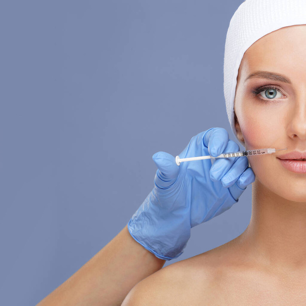 Doctor injecting in a beautiful face of a young woman. Plastic surgery, skin lifting and aesthetic medicine concept. - Фото, зображення