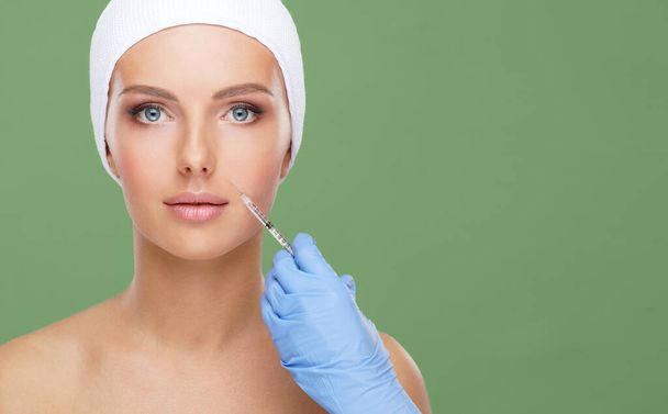 Doctor injecting in a beautiful face of a young woman. Plastic surgery, skin lifting and aesthetic medicine concept. - Photo, Image
