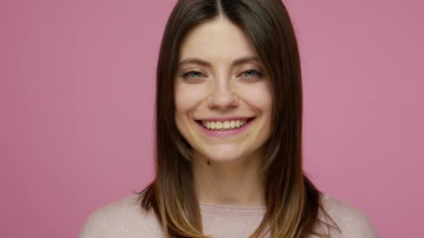 Closeup portrait of charming young brunette woman looking at camera with kind toothy smile, natural beauty and face skin care, positive happy emotions. indoor studio shot isolated on pink background - Séquence, vidéo