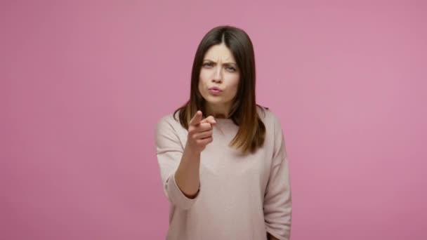 Hey you! Strict displeased brunette woman accusing at camera and pointing warning finger, blaming for mistake, scolding with serious bossy expression. indoor studio shot isolated on pink background - Imágenes, Vídeo