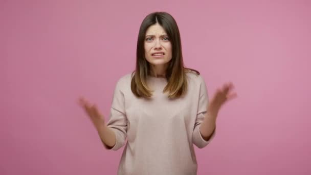 How could you! Depressed brunette woman looking with upset disappointed face and raising hands with indignant expression, asking why, what problem. indoor studio shot isolated on pink background - Кадры, видео