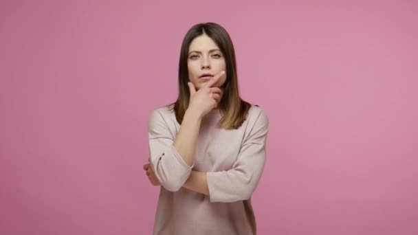 Pensive brunette woman rubbing chin while solving serious problem in mind, nodding approvingly, thinking over smart idea, pondering and musing answer. indoor studio shot isolated on pink background - Metraje, vídeo