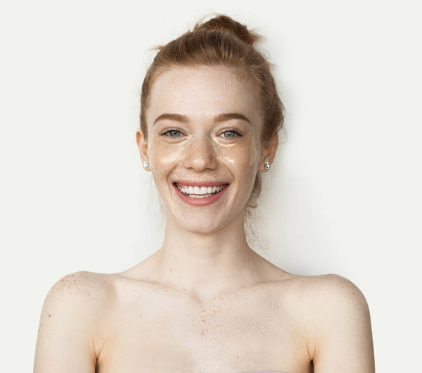 Freckled caucasian woman with naked shoulders and red hair smiling camera on a white background - Foto, Bild