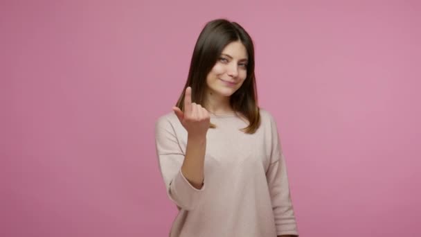 Hey you, lucky, come here to me! Lovely happy brunette woman inviting to follow hither, making beckoning finger gesture, flirting and smiling playfully. indoor studio shot isolated on pink background - Footage, Video