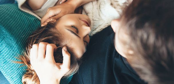 Adorável jovem caucasiano deitado em seu namorado e sorrir com os olhos fechados no sofá
 - Foto, Imagem