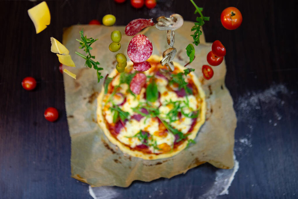 overhead top view of pizza with tomatoes cheese salami salad cooking - 写真・画像