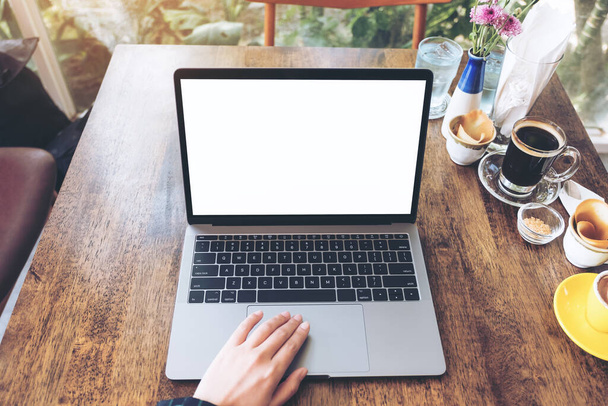 Top view makieta obrazu dłoni za pomocą i wpisując na laptopie z pustym białym ekranem pulpitu i filiżanek kawy na drewnianym stole - Zdjęcie, obraz