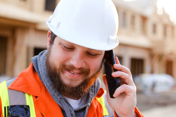 Portret van ingenieur in gesprek met smartphone op bouwplaats. - Foto, afbeelding