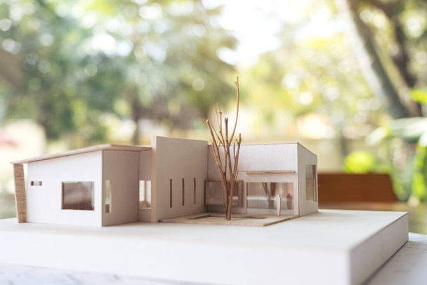 Un modèle d'architecture avec papier dessin boutique et ordinateur portable sur la table au bureau avec fond de nature floue - Photo, image
