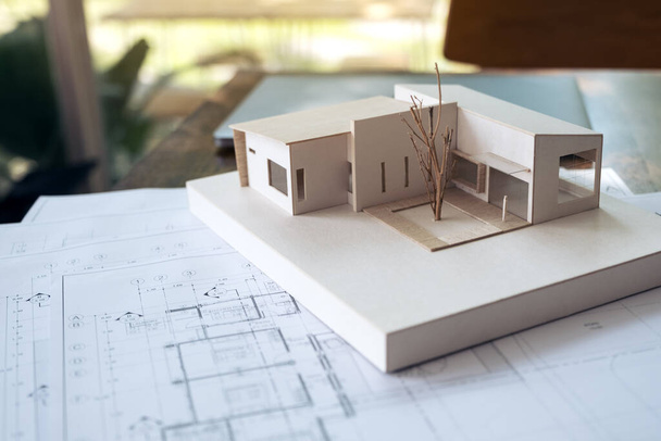 An architecture model with shop drawing paper and laptop on table in office with blur nature background - Photo, Image