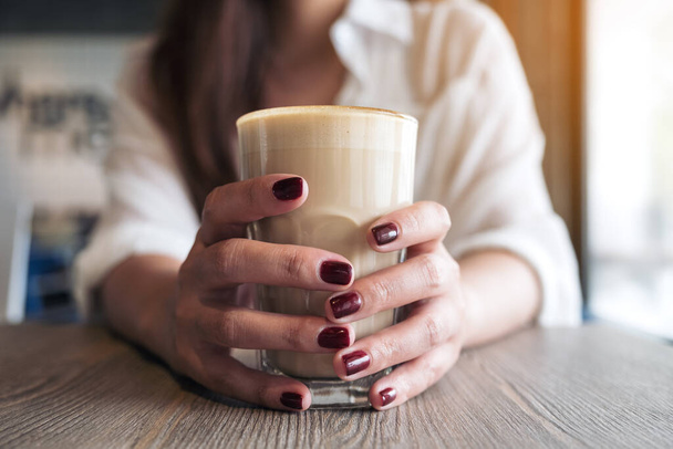 Lähikuva kuva naisen kädet punaiset kynnet väri tilalla lasi kahvia  - Valokuva, kuva