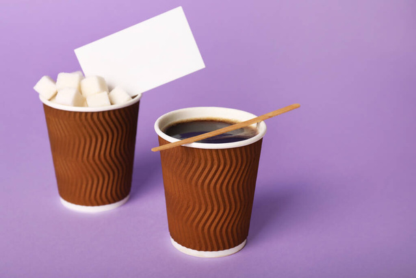 Takeaway cups of coffee with sugar business card on color background - Photo, Image