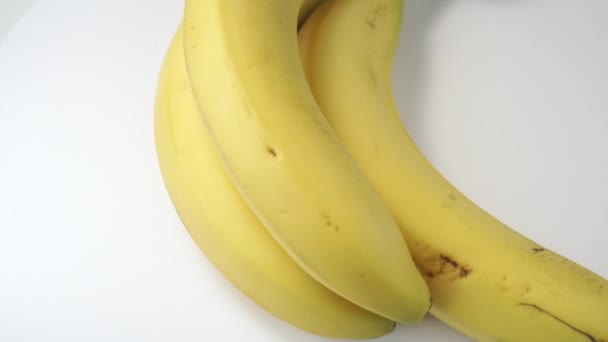 Un mazzo di banane primo piano ruota su uno sfondo bianco. Frutto maturo nutriente per dieta - Filmati, video