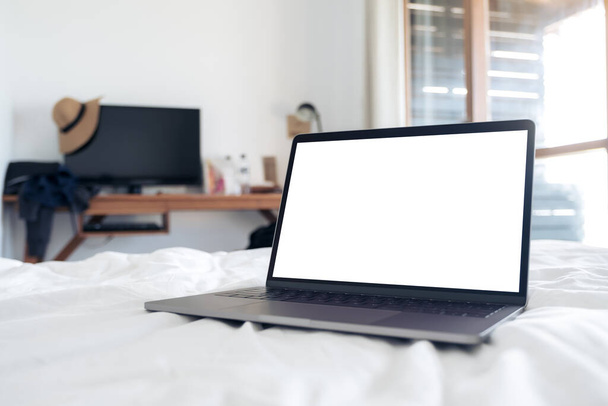 ベッドルームでベッドの上に空白の白いデスクトップ画面とラップトップのモックアップイメージ - 写真・画像