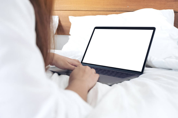 Imagen burlona de una mujer acostada en una cama, utilizando y escribiendo en el ordenador portátil con teclado blanco en blanco de la pantalla de escritorio
  - Foto, imagen