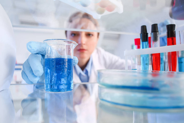 Вчений бере скляний посуд з полиці в лабораторії
 - Фото, зображення