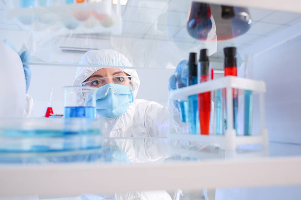 Wissenschaftler holt im Labor Gläser aus dem Regal - Foto, Bild