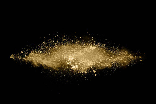 Explosión de polvo dorado sobre fondo negro. Congelar movimiento. - Foto, imagen