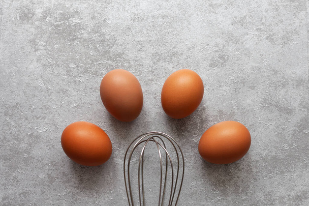 Chicken eggs and whisk in the kitchen - Photo, image