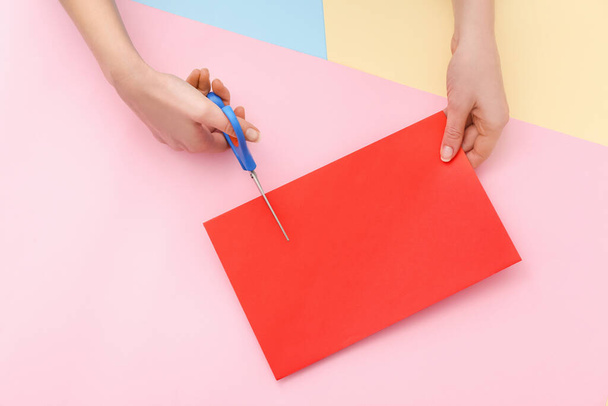 Ręce kobiet cięcia arkusza papieru na tle koloru - Zdjęcie, obraz